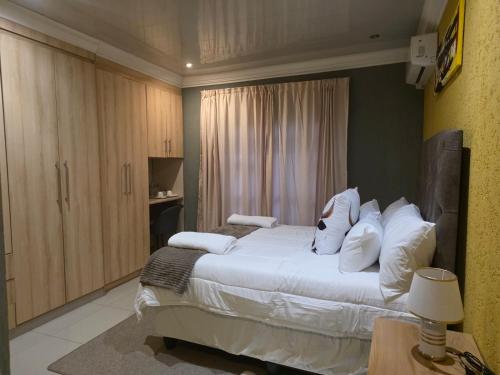 a bedroom with a large bed with white pillows at RIER Guesthouse in Pretoria