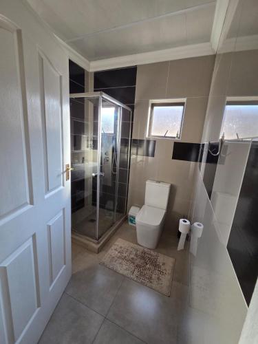 a bathroom with a toilet and a glass shower at RIER Guesthouse in Pretoria