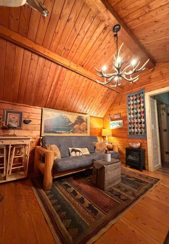 a living room with a couch and a chandelier in a cabin at The Dapper Duck Log Cabin in Cosby
