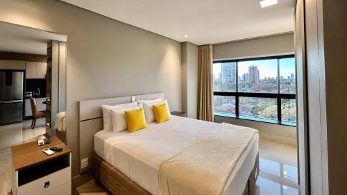 a bedroom with a bed with yellow pillows and a window at Flat Elegante, Confortável e Com Uma Bela Vista in Campo Grande