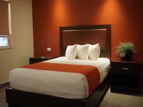 a bedroom with a large bed with an orange wall at Hotel Buen Valle in Torreón