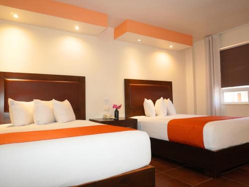 a hotel room with two beds with orange and white sheets at Hotel Buen Valle in Torreón