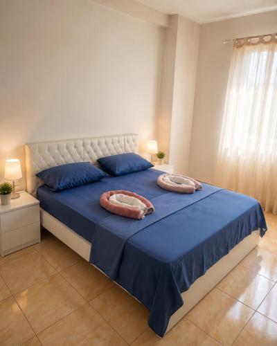 a bedroom with a blue bed with two pillows on it at Cozy Apartment Astiri in Tirana
