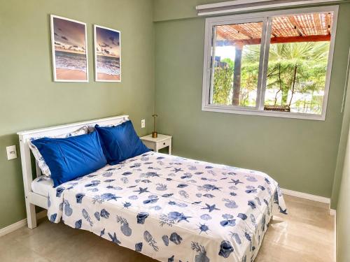 a bedroom with a bed with blue pillows and a window at Village Baixio Garden in Baixio