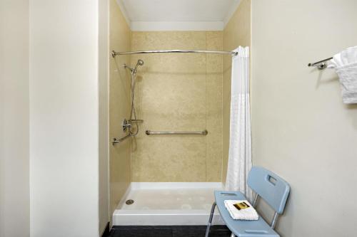 a bathroom with a tub and a shower with a blue chair at Best Western Plus the Four Corners Inn in Farmington