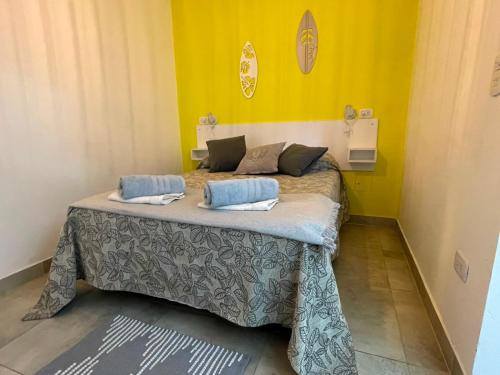 a bed in a room with a yellow wall at Apart Hotel RioSol - Monoambientes in Concepción del Uruguay