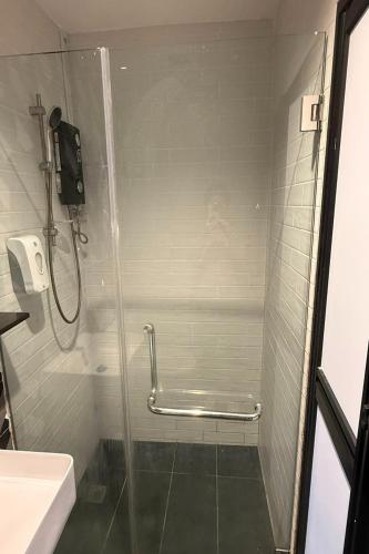 a shower with a glass door in a bathroom at GoStay Pods at Perak Road in Singapore