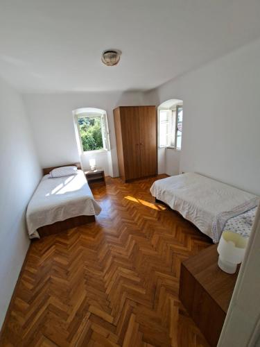 a bedroom with two beds and a wooden floor at Macmalić in Zbičina