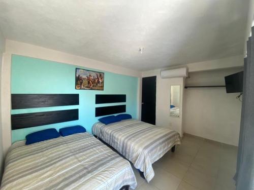 two beds in a bedroom with blue walls at Hotel Bora Bora Acapulco in Acapulco