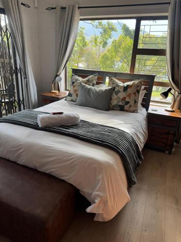 a large bed in a room with a large window at Hidden Gem in George