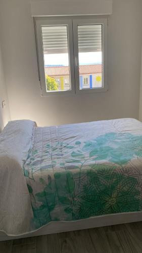 a bed in a bedroom with two windows at Villa HEGODEI in A Pobra do Caramiñal