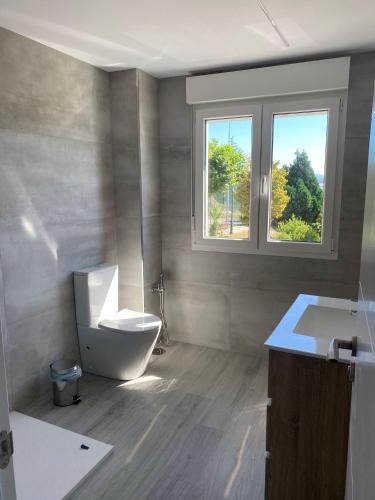 a bathroom with a toilet and a sink and a window at Villa HEGODEI in A Pobra do Caramiñal