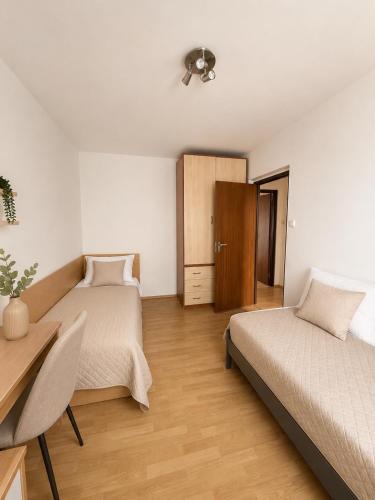 a bedroom with two beds and a desk and a table at Apartnám Harmony in Martin