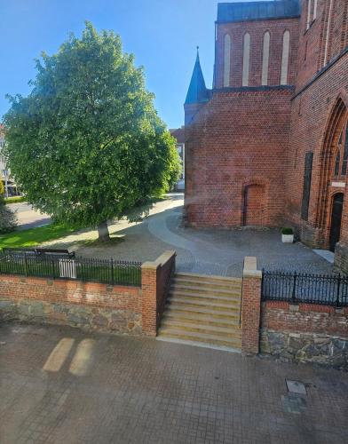 a brick building with a staircase in front of a tree at Apartament Merkury in Koszalin