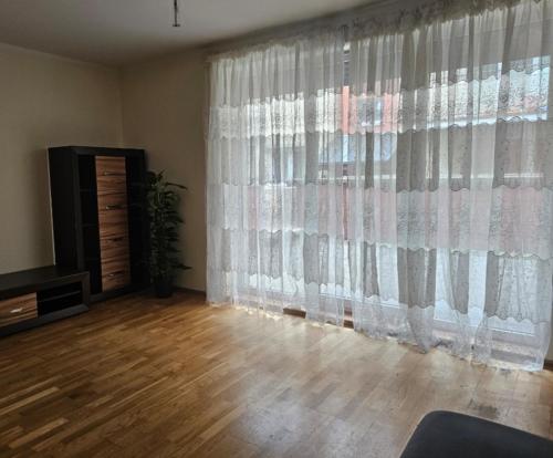 a living room with a large window with curtains at Apartament Merkury in Koszalin