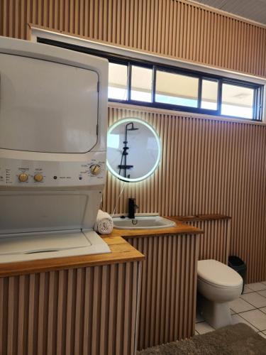 a bathroom with a toilet and a sink and a mirror at Tropical Breeze Apartments in Paramaribo