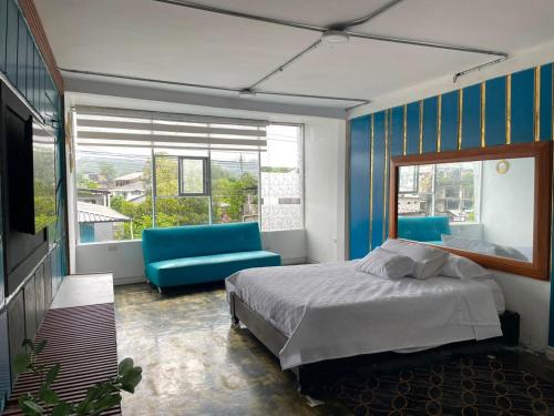 a bedroom with a bed and a couch and a window at Hotel Cristian in Puyo