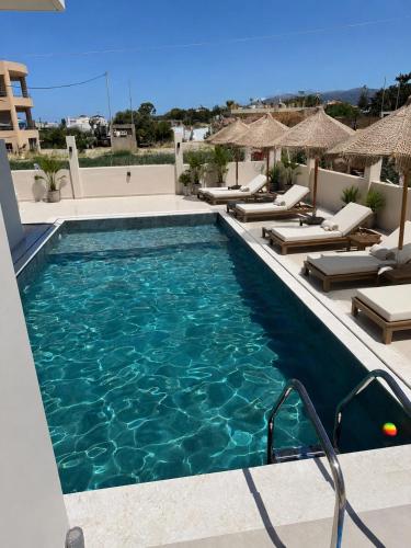 a swimming pool with chaise lounge chairs next to a swimming pool at Thea Stays in Kato Gouves