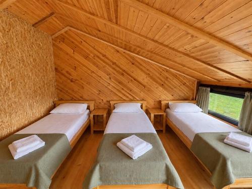 two beds in a room with wooden ceilings at Chalet Hatsvali - Ushba Viewpoint Rooms & Café in Mestia