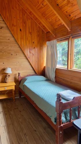 a bedroom with a bed in a wooden cabin at Selene Malen 5 in Villa Pehuenia
