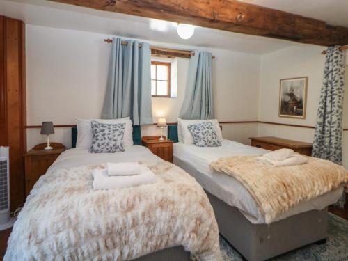 two beds in a bedroom with blue curtains at Slade Cottage in Ashbourne
