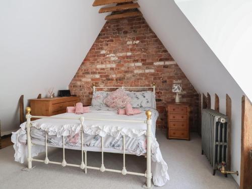 a bedroom with a white bed with a brick wall at 1 Fountain Cottages in Tarporley