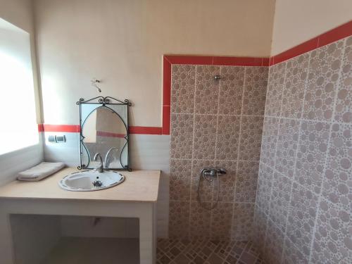 a bathroom with a sink and a shower with a mirror at Hostel amodou in Tinerhir