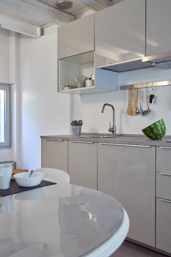 a kitchen with white cabinets and a glass table at Sottomarina Suite Palazzo Storico in Chioggia