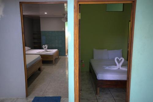 a bedroom with two beds with white sheets and a mirror at Casa Delfín in Tortuguero