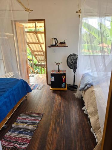 a bedroom with a bed and a fan and a window at Casa de Deli in Ilha de Boipeba