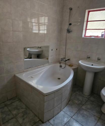 a white bathroom with a tub and a sink at JJK free Breakfast in Barberton