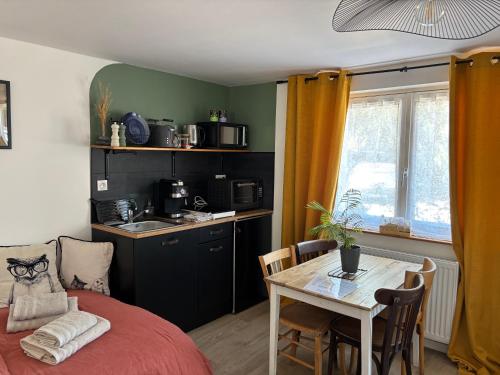 a room with a table and a kitchen with a bed at le Studio Balnéo des Cocons de Mel in Quinssaines
