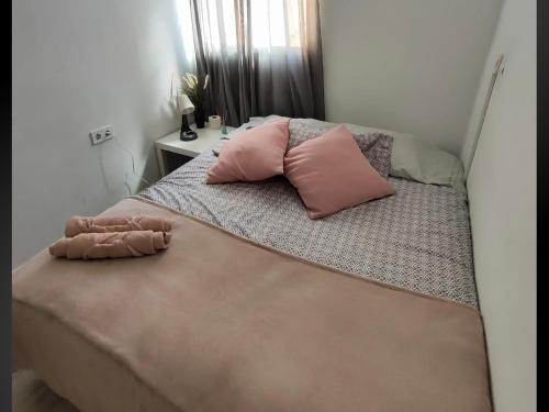 a bed with two pink pillows on top of it at Alojamiento cerca de la Playa in Valencia