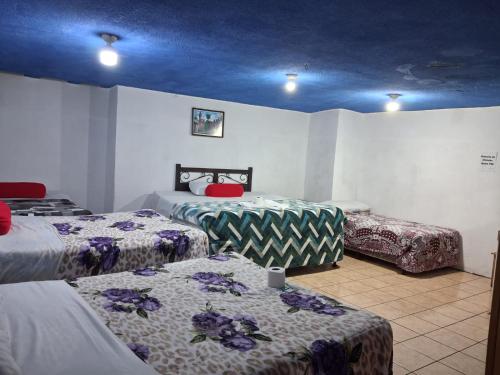 a room with three beds and a blue ceiling at hotel kasa kamelot parque in Quetzaltenango