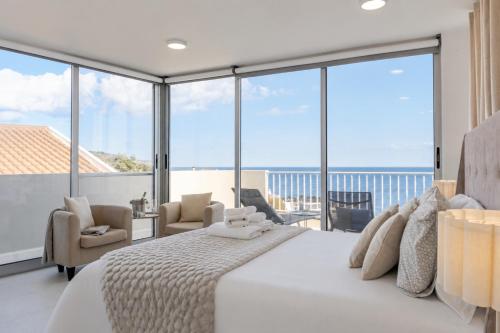 a bedroom with a large white bed and windows at Casa Rosa Panoramic Seaview in Lagoa