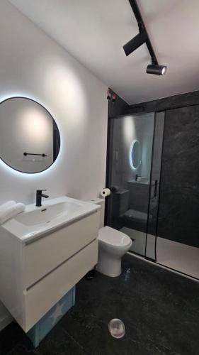 a bathroom with a sink and a toilet and a mirror at Suite Marina Gallega in Oya