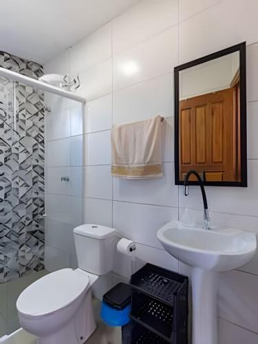 a white bathroom with a toilet and a sink at Chalés da Guarda do Embaú in Guarda do Embaú