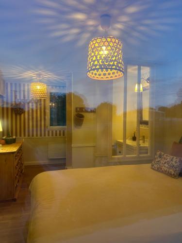 a bedroom with a bed and a chandelier at Le Nid de Lou in Aire
