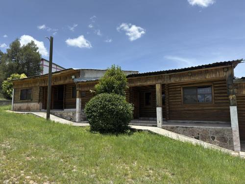 a log cabin with a green field in front of it at Hotel Nuevo Barrancas del Cobre in Creel