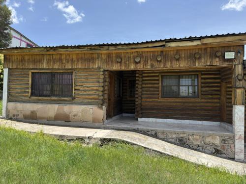 a log cabin with a porch and two windows at Hotel Nuevo Barrancas del Cobre in Creel