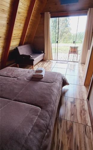 a large bed in a room with a large window at Chalé do Campo in Palmeira
