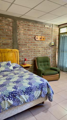 a bedroom with a bed and a green chair at Costa Azul 2 in Villa Pehuenia