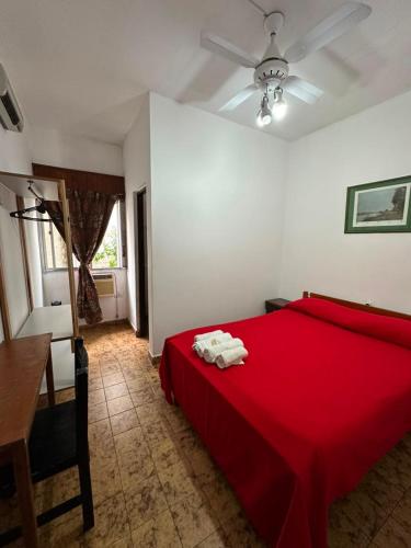 a bedroom with a bed with red sheets and a desk at Hotel San Jose in Federación