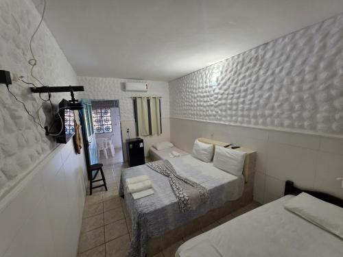 a bedroom with two beds and a chair in it at Pousada Golfinho in Galinhos