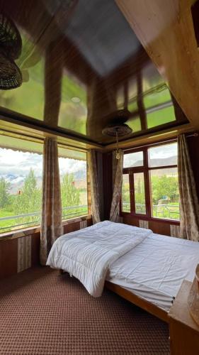 a bedroom with a large bed in front of windows at Bagh Rustum Guest House in Holshāl