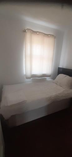 a bedroom with a bed with a window with white sheets at Our Guests Are Royal (KE) in Higham Ferrers