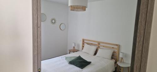 a bedroom with a bed with white sheets and green pillows at L'ecrin de Provence in Beaumes-de-Venise
