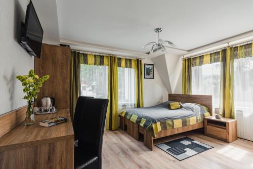 a bedroom with a bed and a desk with a television at Willa Śnieżynka in Szczawnica