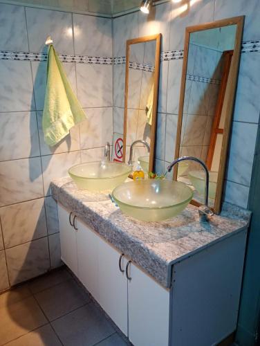 a bathroom with two sinks and two mirrors at Hostal Casona del Canto in Los Andes