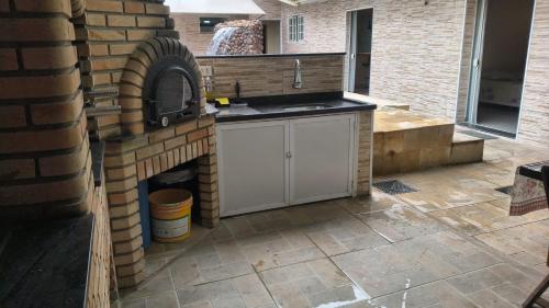 an outdoor kitchen with a brick oven in a patio at Linda casa Edícula "fundos do terreno" com piscina in Itanhaém